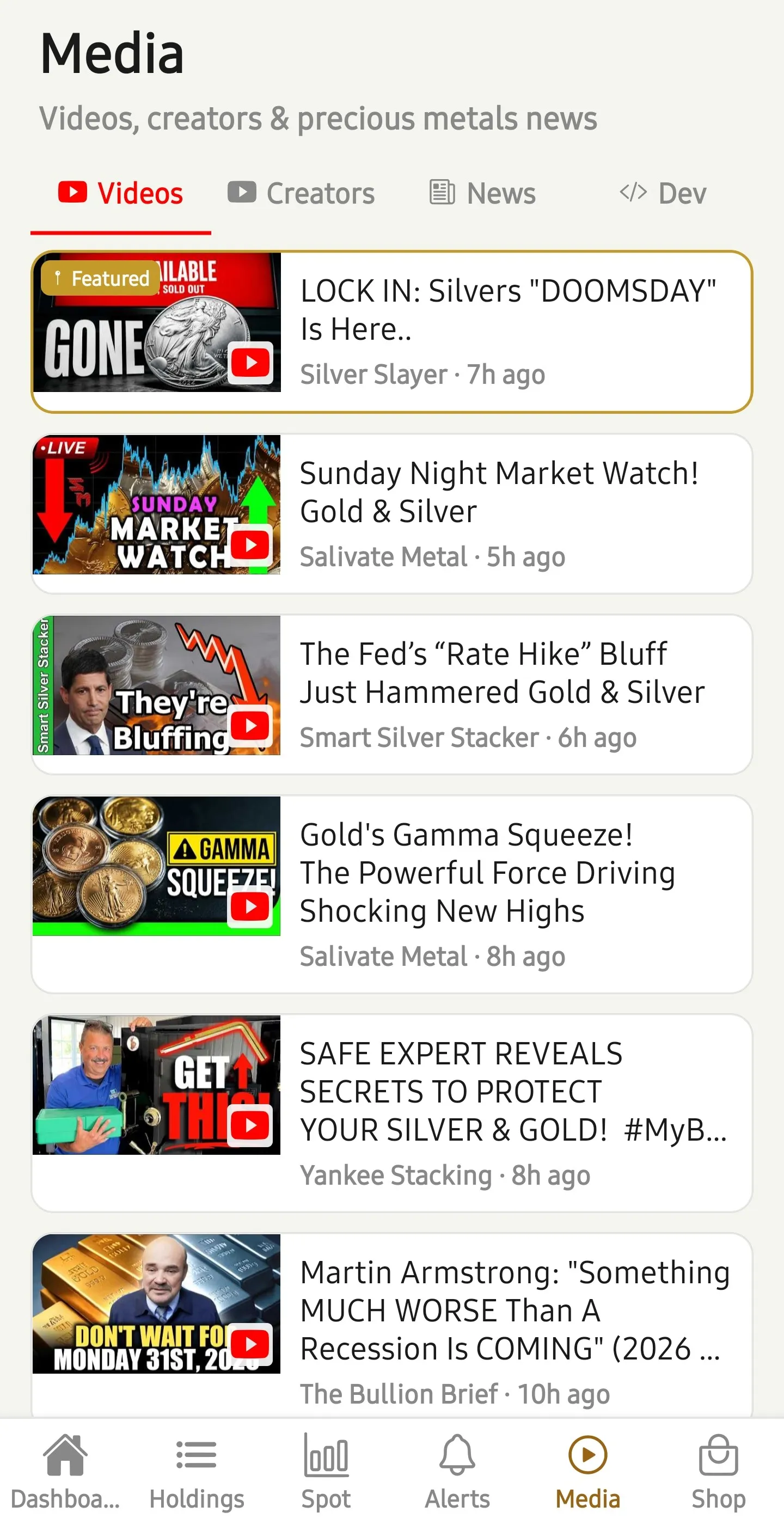 BullionTally in-app Videos feed with a partner's latest YouTube video pinned at the top as the Featured video, above other precious-metals creator uploads